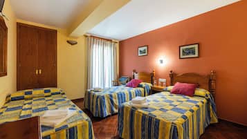 Habitación de hotel con dos camas, cabeceros de madera, un armario de madera, una silla y una ventana con cortinas.