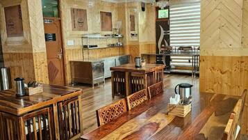 Un restaurante con paneles de madera, una larga mesa de comedor y una zona de cocina.