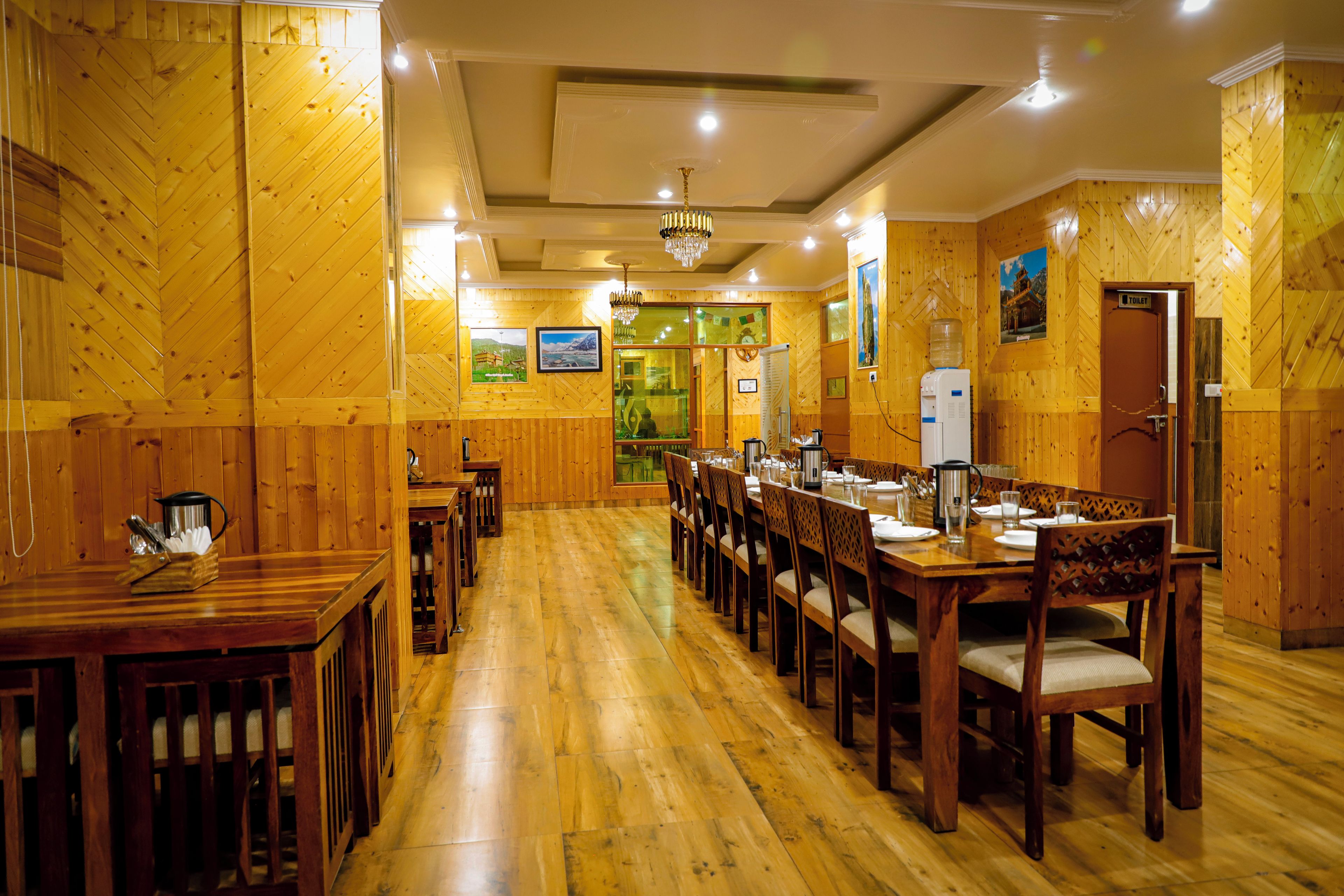 Ein Restaurant mit Holzwänden und -böden, mehreren Tischen und Stühlen sowie einem Kronleuchter.