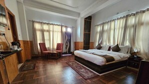 A bedroom with a large bed, a desk, and a chair. - Hotel Sarahan Inn (Rampur)