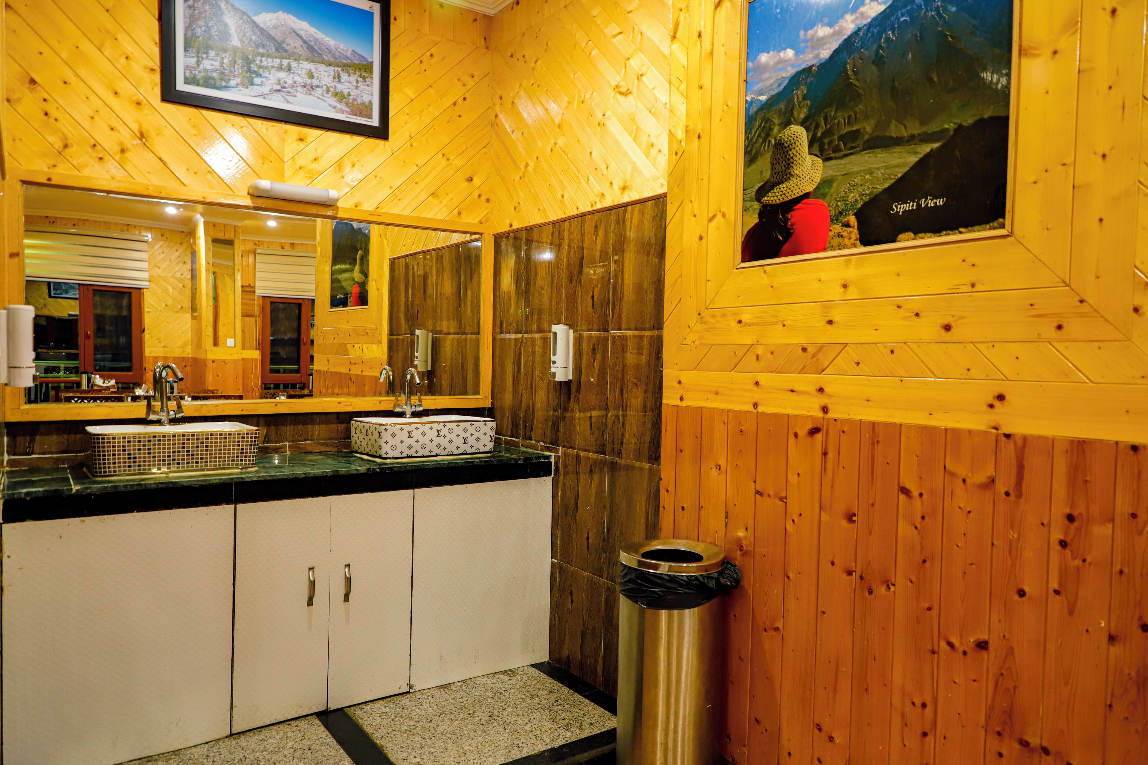 Un intérieur en bois, avec un plancher en bois, un évier avec un miroir et une poubelle.