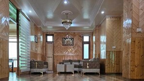 A spacious room with wooden paneling, a chandelier, and a sofa set. - Hotel Sarahan Inn (Rampur)
