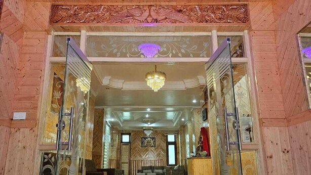 A spacious lobby with a checkered floor, wooden paneling, and a chandelier. - Hotel Sarahan Inn (Rampur)
