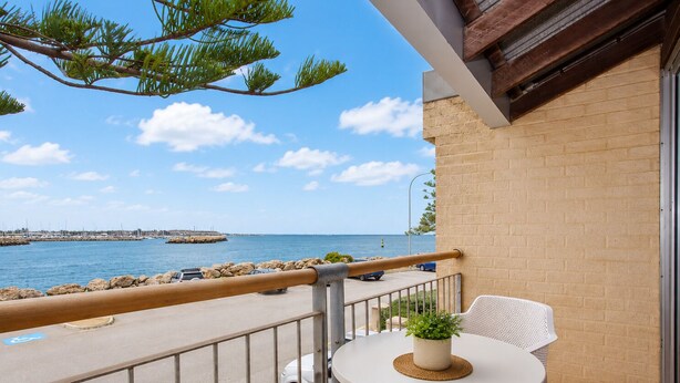 A balcony with a view of the sea, a white table with a plant, and a white chair. - Wake up to spectacular harbour views and watch ships glide past from your private balcony. <br>Mariners Lookout is a spacious waterfront apartment just minutes from Fremantle's cafés, restaurants, Bathers Beach and the Rottnest Ferry. <br>Perfect for (Fremantle)