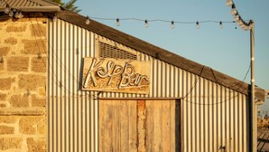 A rustic building with a corrugated metal exterior, a wooden door, and a sign that reads 'Kip's Bar.' - Wake up to spectacular harbour views and watch ships glide past from your private balcony. <br>Mariners Lookout is a spacious waterfront apartment just minutes from Fremantle's cafés, restaurants, Bathers Beach and the Rottnest Ferry. <br>Perfect for (Fremantle)
