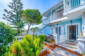 Un bâtiment à deux étages doté d’un balcon, d’un escalier et d’un jardin où poussent différentes espèces de plantes.