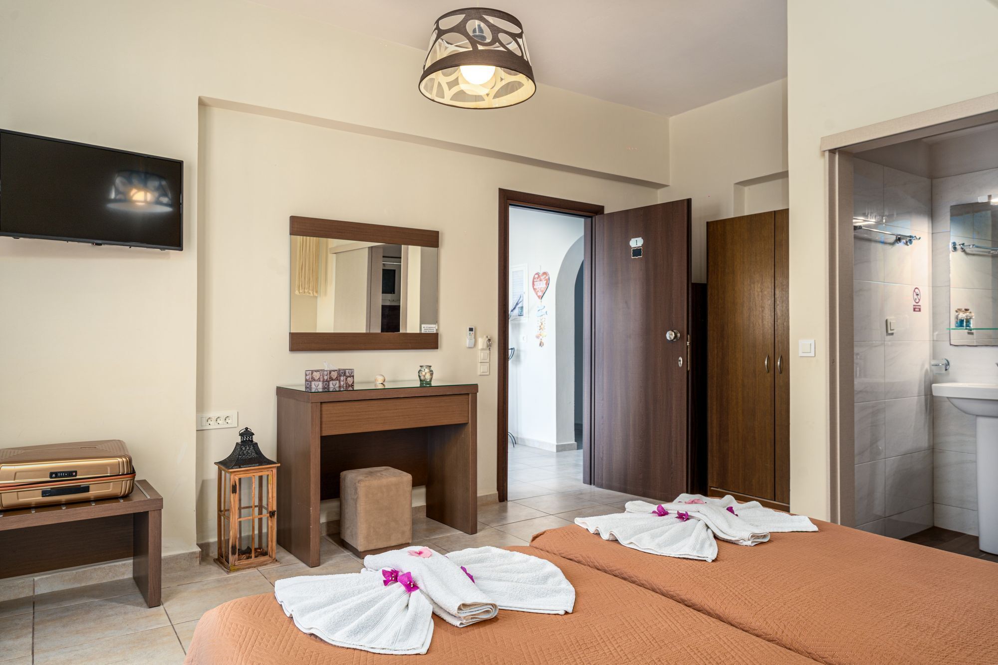 A hotel room with a bed, a desk, a TV, a mirror, a wardrobe, and a bathroom.