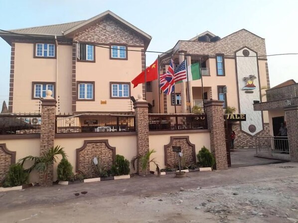 A multi-story building with a stone facade, multiple windows, and a gated entrance. - Sunnyvale Hotel (Lekki)
