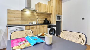 Una cocina moderna con armarios de madera, microondas, lavadora y comedor con mesa y sillas.