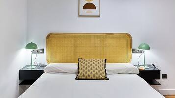 A neatly made bed with a yellow headboard, two bedside tables with lamps, and a framed picture on the wall.