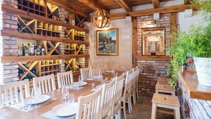 A restaurant with a brick wall, wooden shelves with bottles, a dining table set for six, and a hanging light fixture. - Charming 2-bedroom apartment with AC, WiFi in enchanting Dubrovnik (Dubrovnik)