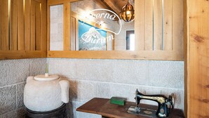 A rustic room with a wooden ceiling, a stone wall, a wooden cabinet, a vintage sewing machine, and a large stone pot. - Charming 2-bedroom apartment with AC, WiFi in enchanting Dubrovnik (Dubrovnik)