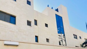 A modern building with a beige facade, multiple windows, and a prominent blue glass entrance. - mount houssein (Amman)