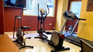 A home gym with exercise equipment, a TV, and a chandelier. - mount houssein (Amman)