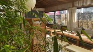 A traditional Japanese-style room with tatami flooring, a low wooden table, and a large window with a view of a bamboo fence. - Hantang Inn Hostel Xi'an (Xi'an)