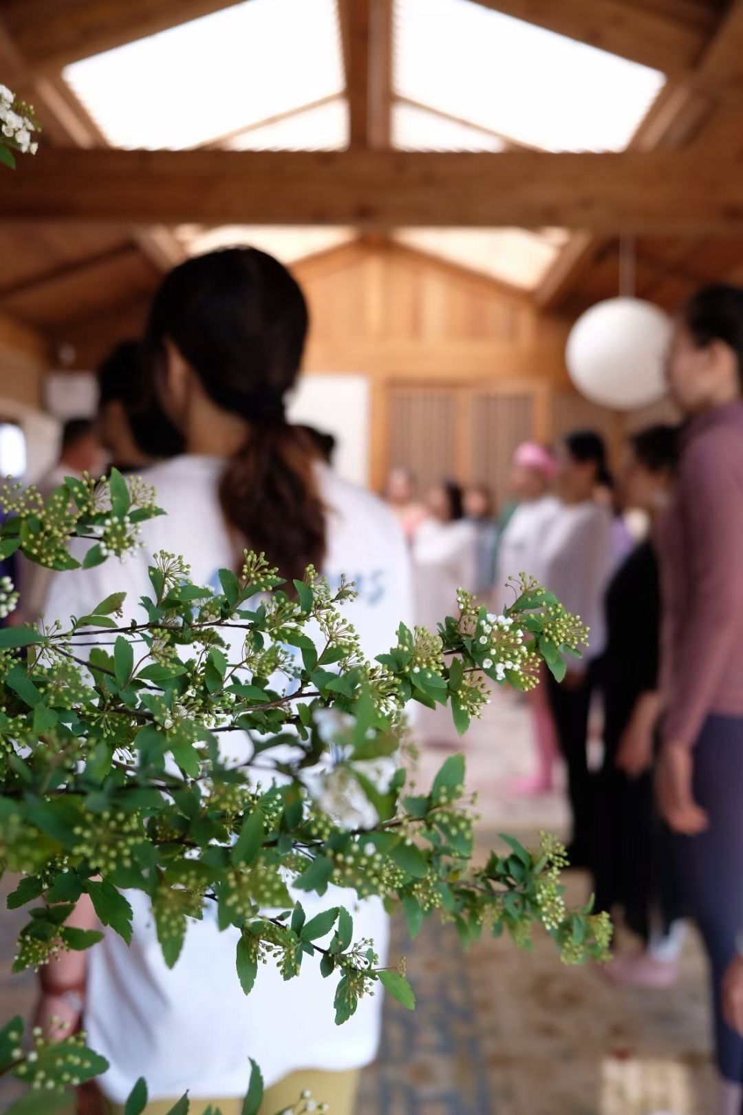 A group of people in a covered outdoor area with a wooden ceiling and a patterned floor.