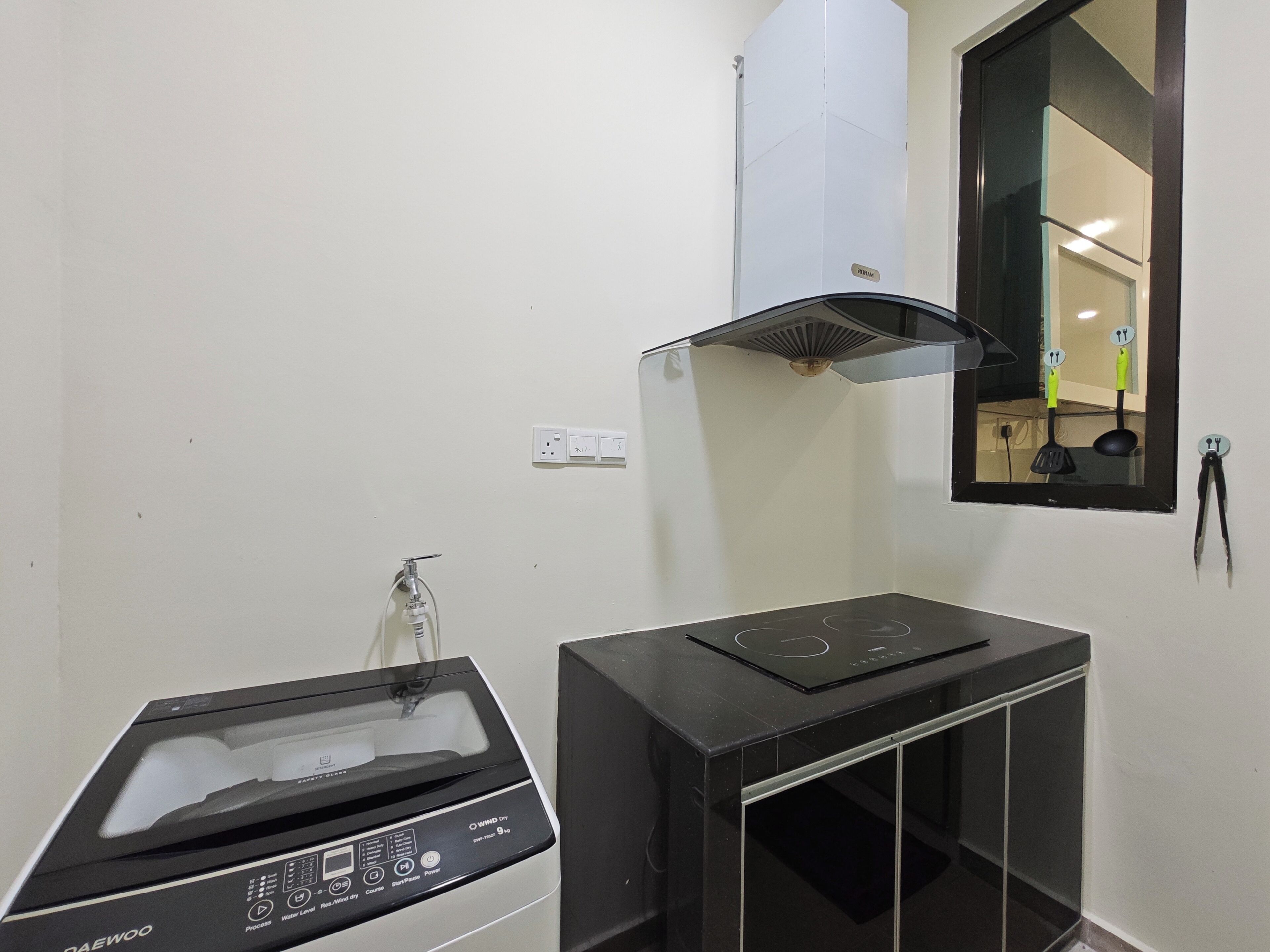 A compact kitchen with a built-in oven, a sink, and a ventilation hood.