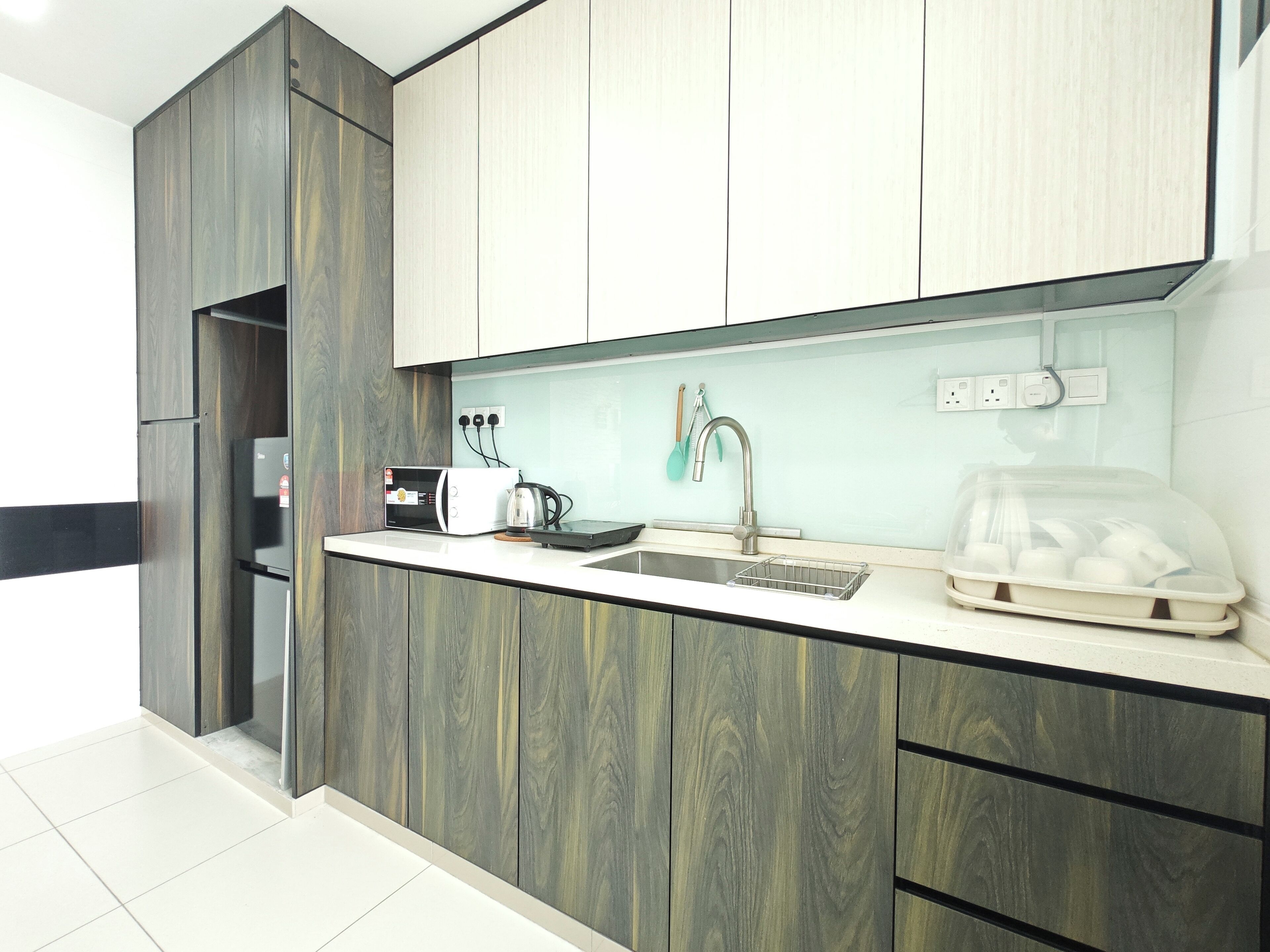 Una cucina moderna con forno a incasso, microonde, bollitore e lavello.