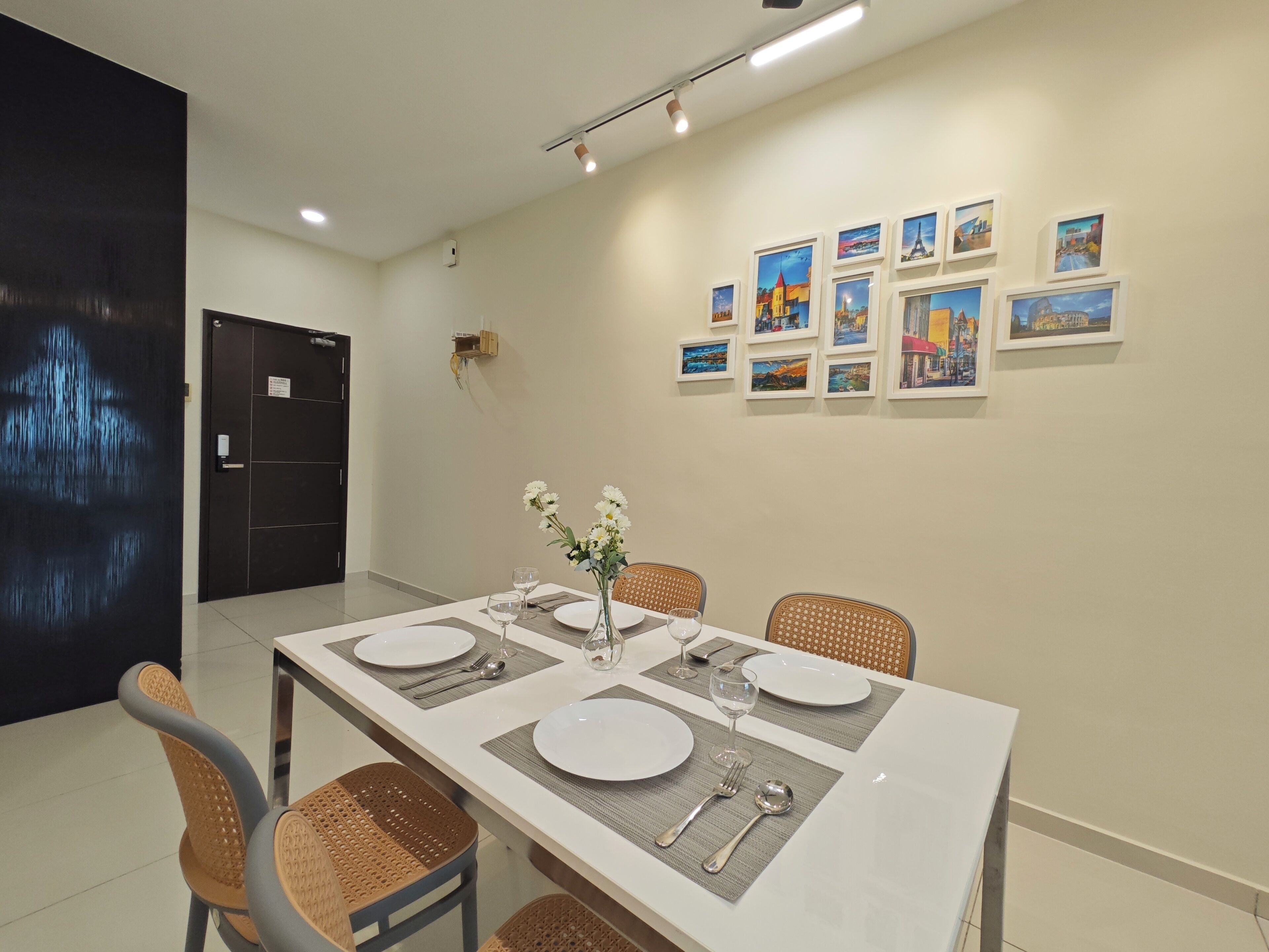 A dining area with a long table set for four, surrounded by wicker chairs.