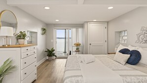 Un dormitorio con cama, cómoda, espejo y vista al exterior.
