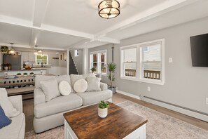 Een ruime woonkamer met een bank, salontafel en een trap naar een keuken.