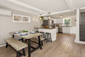 Une cuisine moderne dotée d’un îlot central, d’une table à manger en bois et de tabourets de bar.