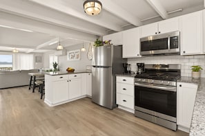 Une cuisine moderne avec des meubles blancs, des appareils en acier inoxydable et un plancher en bois.