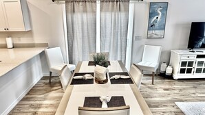 Un comedor con una mesa de madera, sillas blancas y un armario blanco.