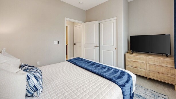 Une chambre à coucher comprenant un lit, un téléviseur, une armoire et un ventilateur de plafond.
