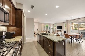 A modern kitchen with a central island, built-in appliances, and a dining area with a large window.