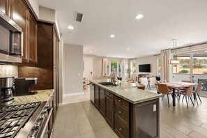 A modern kitchen with dark wood cabinets, a large island with a sink, and a gas stove.