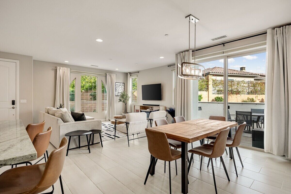 A spacious living area with a dining table, sofas, and a TV.