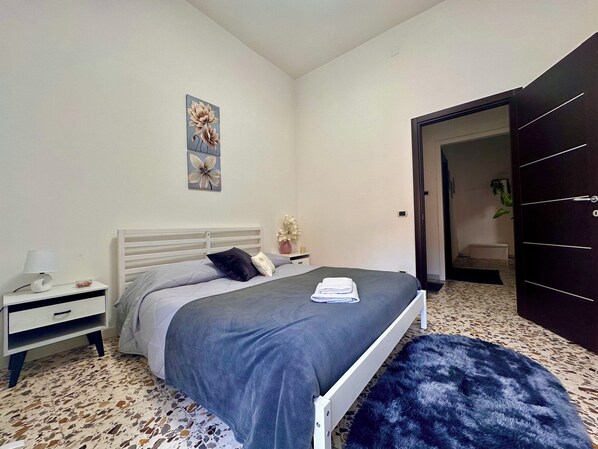 A bedroom with a bed, a nightstand, a wall-mounted artwork, and a dark door. - Green Heart House Napoli (Naples)