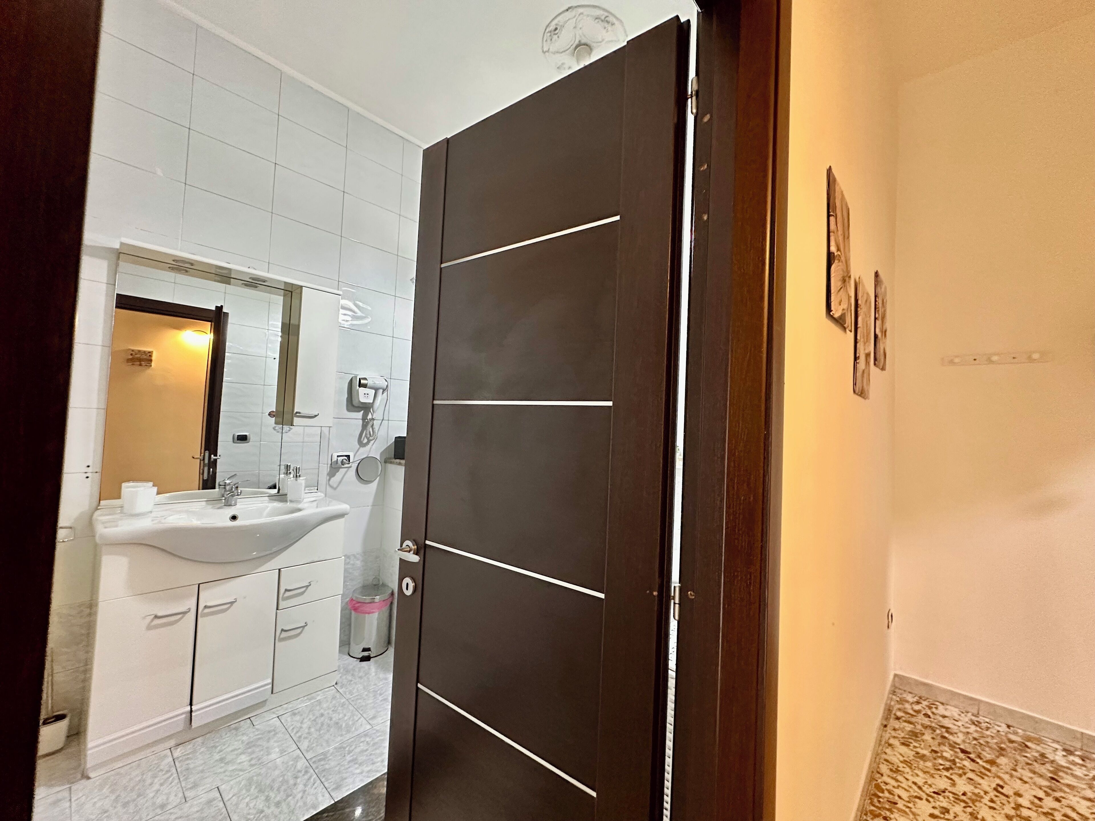A bathroom with a white sink, mirror, and a dark wooden door.