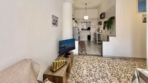 A living room with a TV, a coffee table with decorative items, and a patterned carpet. - Green Heart House Napoli (Naples)