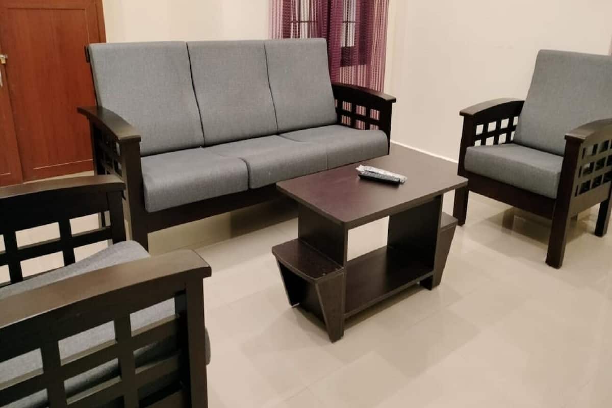 Ein Wohnzimmer mit einer grauen Couch, zwei Holzstühlen und einem dunkelholzigen Couchtisch.