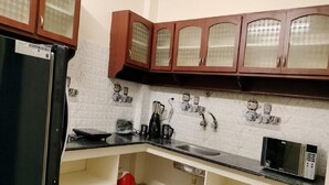 A kitchen with a refrigerator, microwave, and cabinets. - Gokulam Villa (Puducherry)