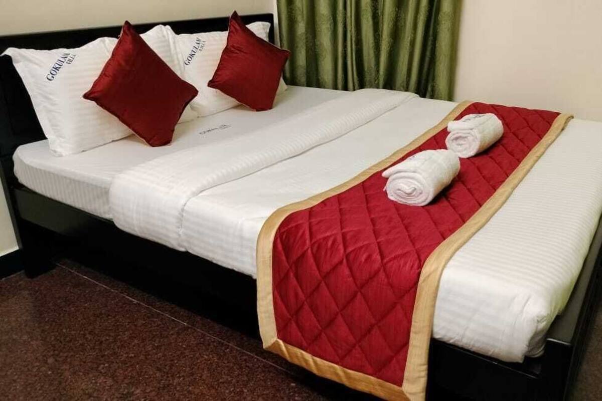 Ein ordentlich bezogenes Bett mit weißen Leinentüchern, roten Kissen und einer roten gesteppten Decke.