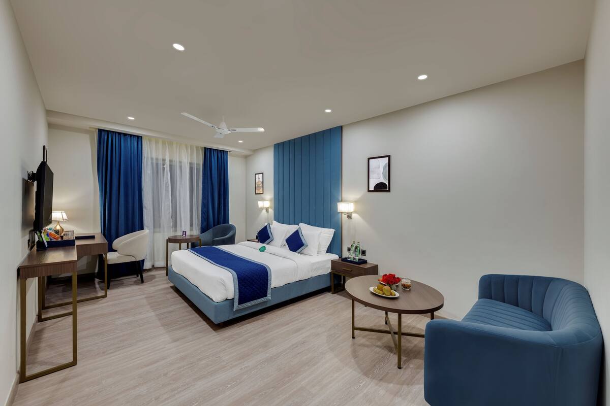 Et moderne hotelværelse med seng, skrivebord, stol, lille bord og sofa.