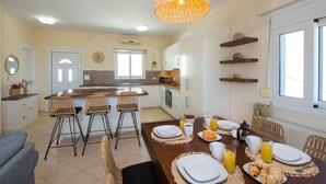 A modern kitchen with white cabinets, a central island, and a dining area set for breakfast.