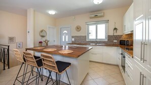 A kitchen with a central island, white cabinets, a microwave, and a clock on the wall.