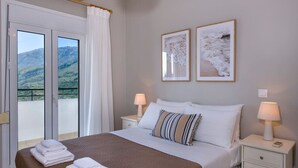 A hotel room with a bed, two bedside tables, a window with curtains, and two framed pictures on the wall.