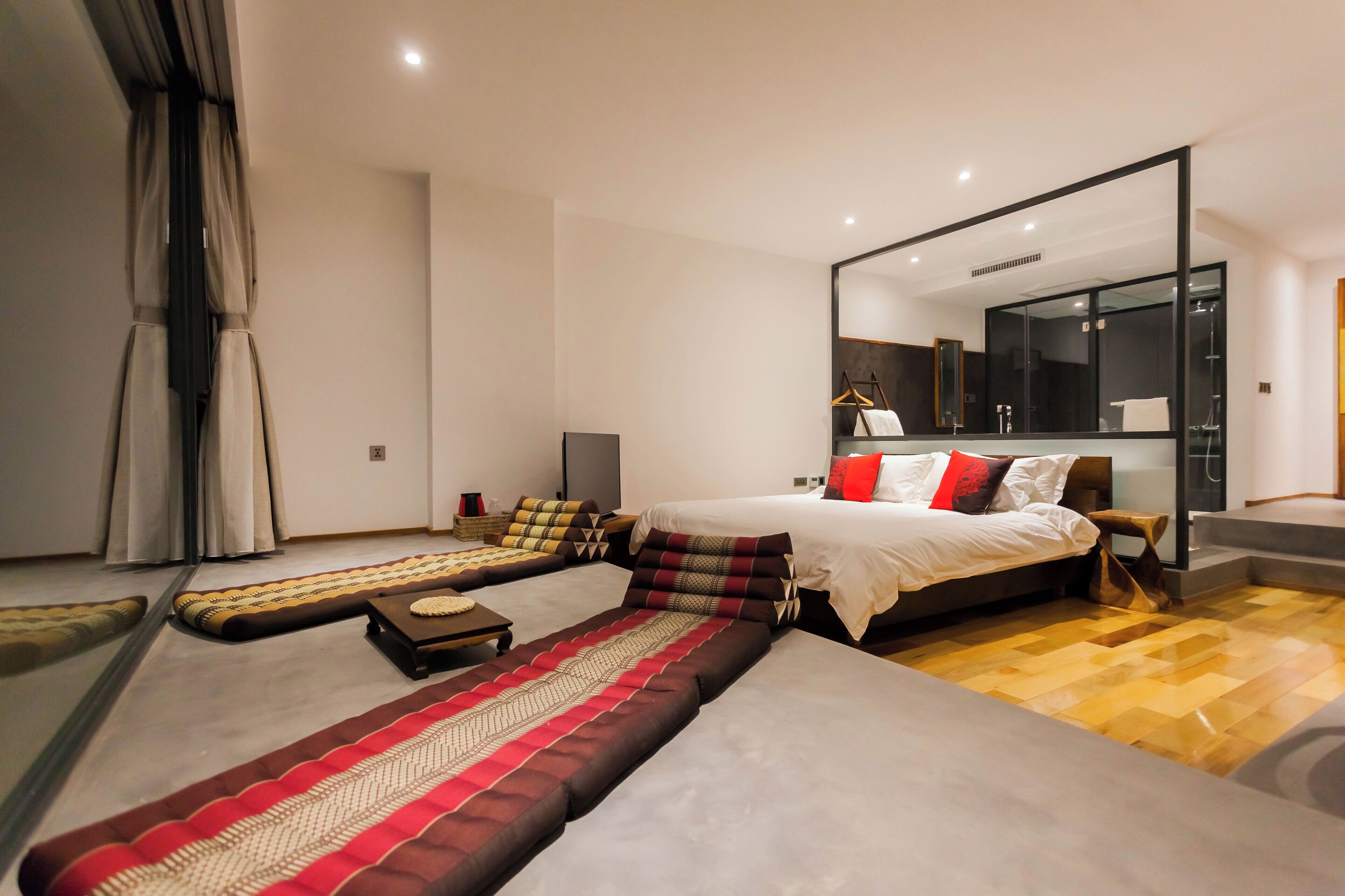 A modern bedroom with a large bed, a sofa, a small table, and a mirror.