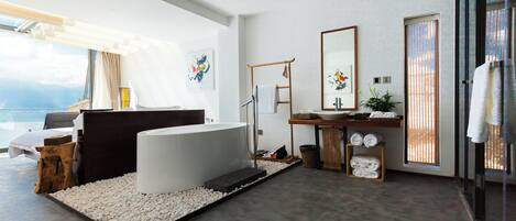 A modern bathroom with a bathtub, a vanity with a mirror, and a large window with a view of the outdoors.