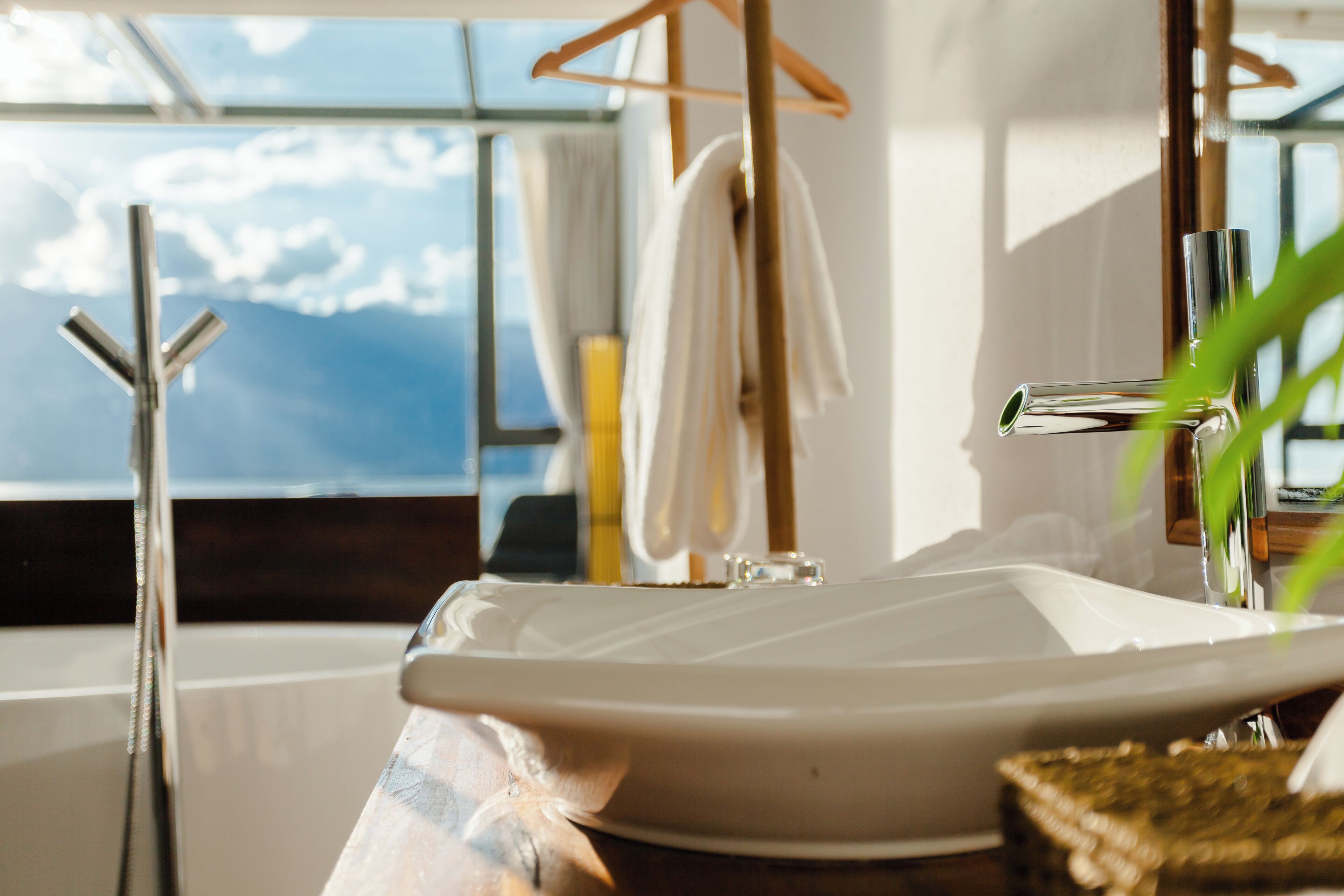 Une salle de bain dotée d’une grande fenêtre, d’un lavabo moderne et d’un porte-serviettes.