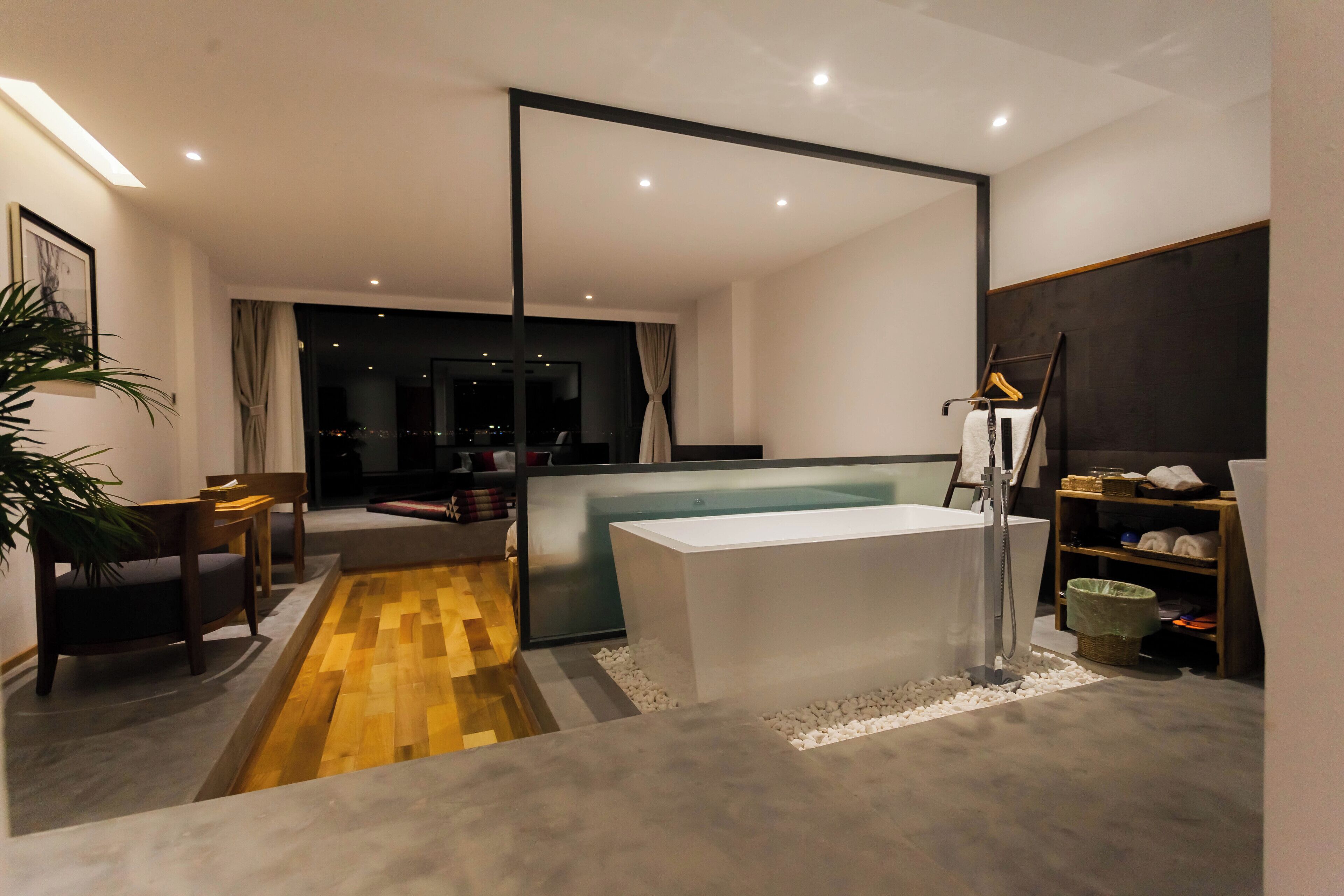 A modern bathroom with a large bathtub, a wooden floor, and a glass shower enclosure.