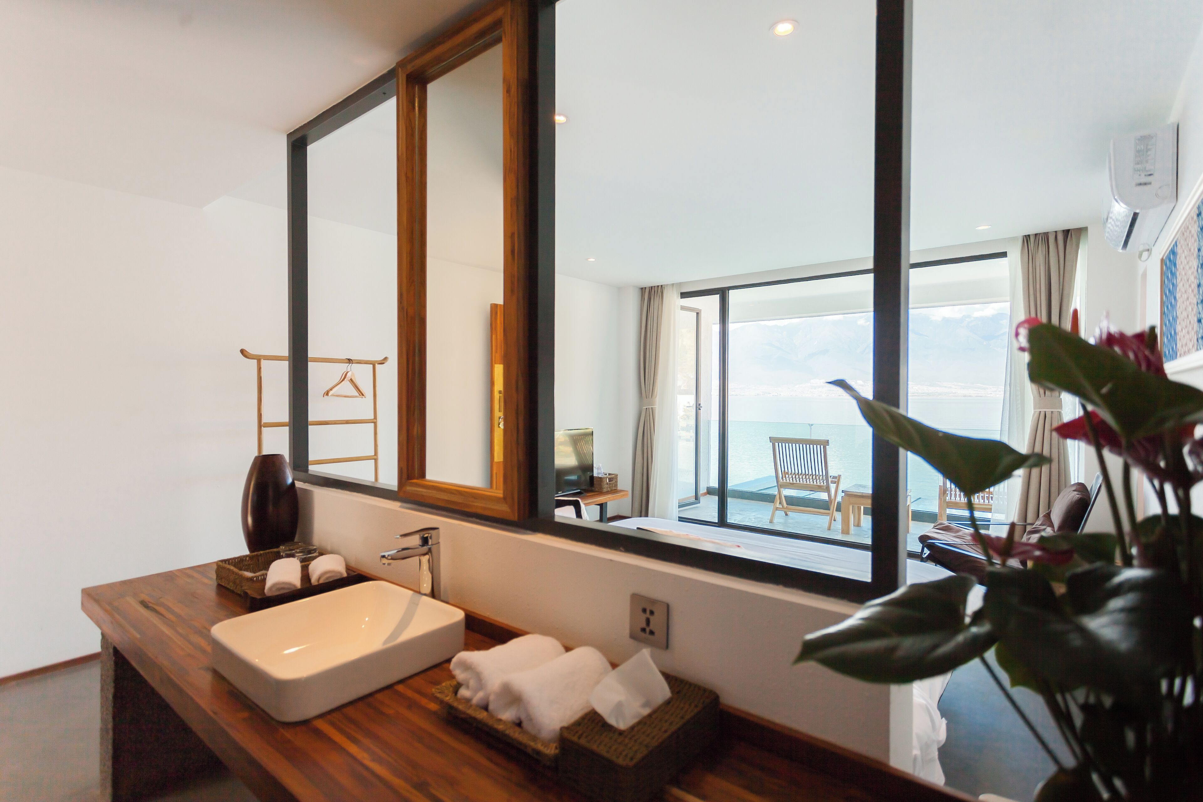 Un baño moderno con un espejo grande, encimera de madera y vistas al balcón.