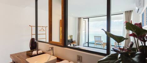 Un baño moderno con un espejo grande, encimera de madera y vistas al balcón.
