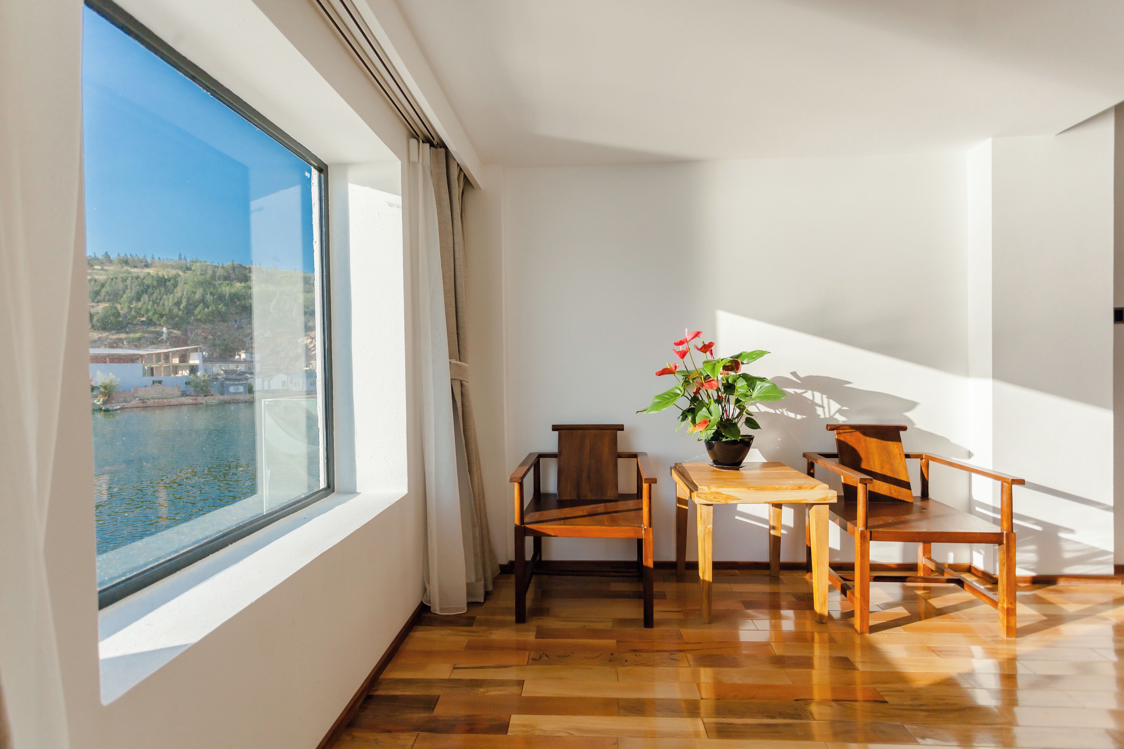 Ein Balkon mit Holzboden, einem Tisch, zwei Stühlen und einem Blumentopf.