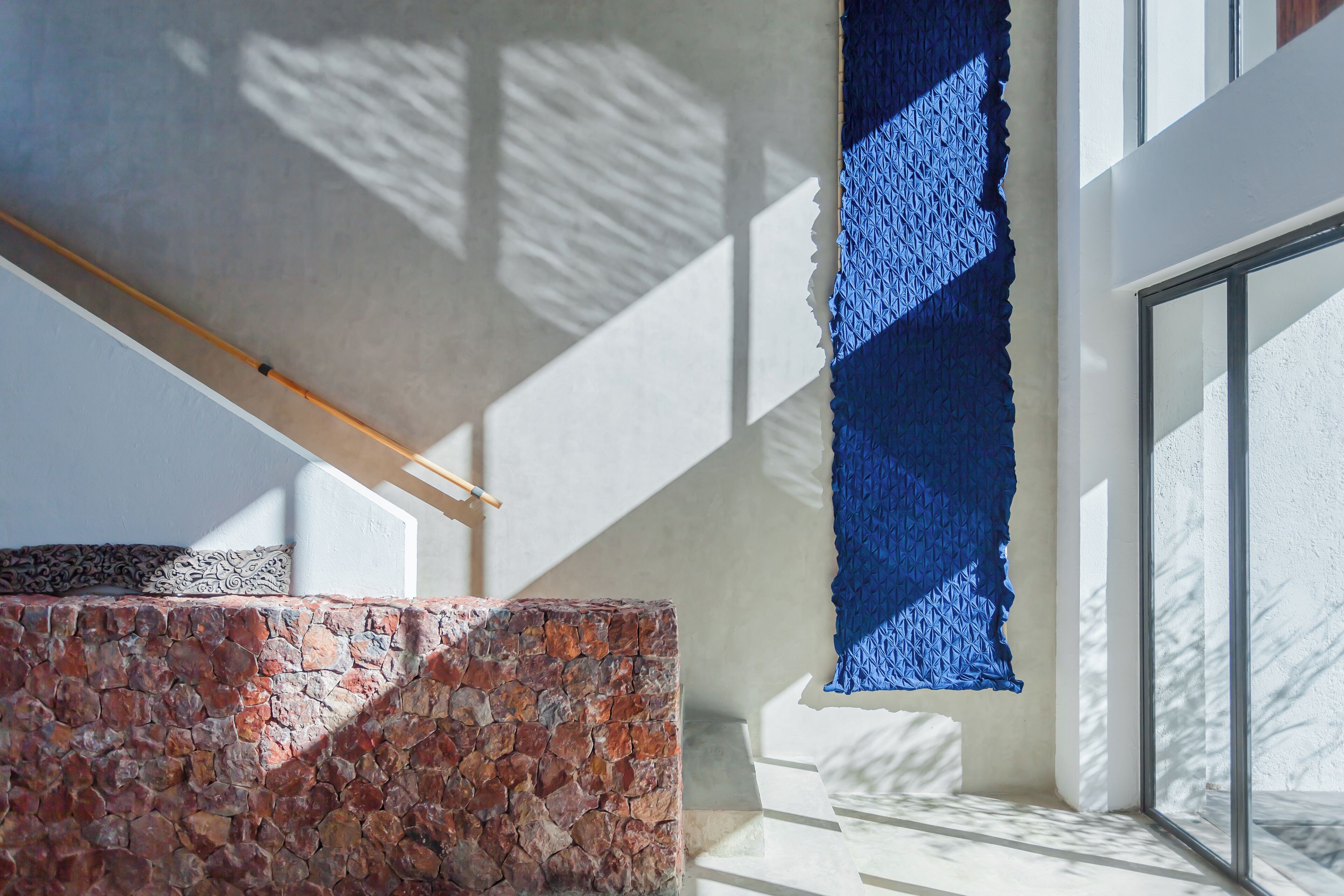Un interior moderno con pared de piedra, viga de madera y pared azul texturizada.